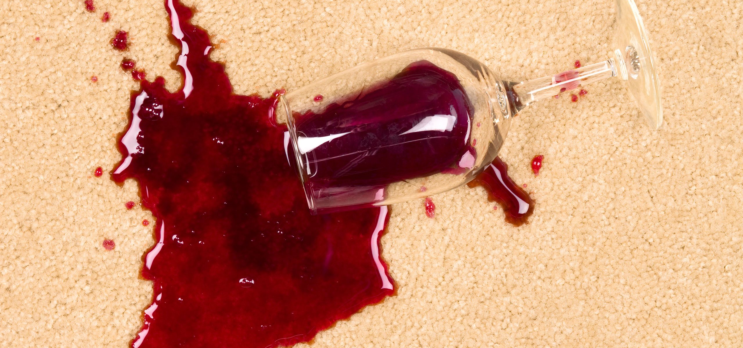 glass of red wine spilled on white carpet